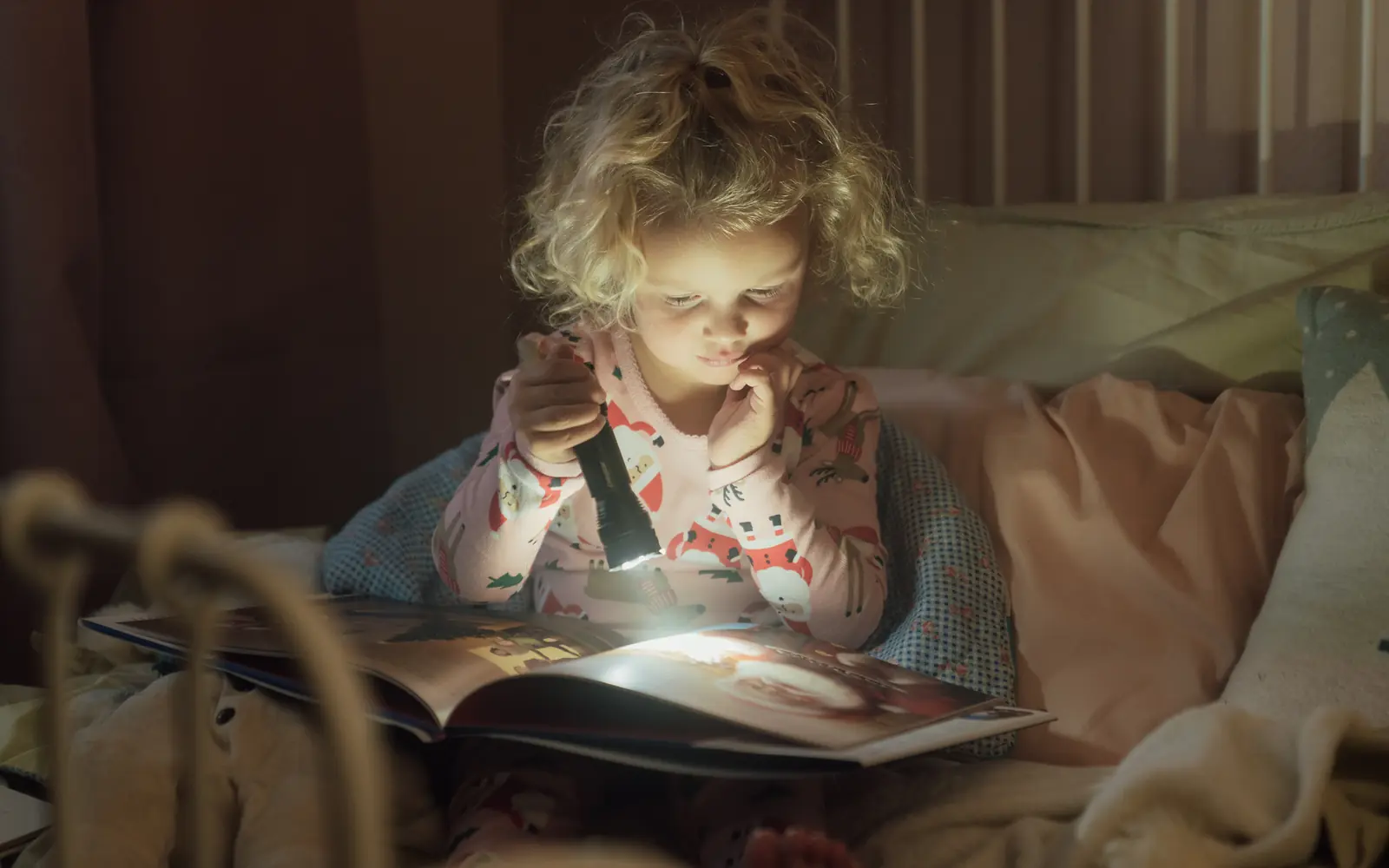 Child reading a storybook by warm lamplight